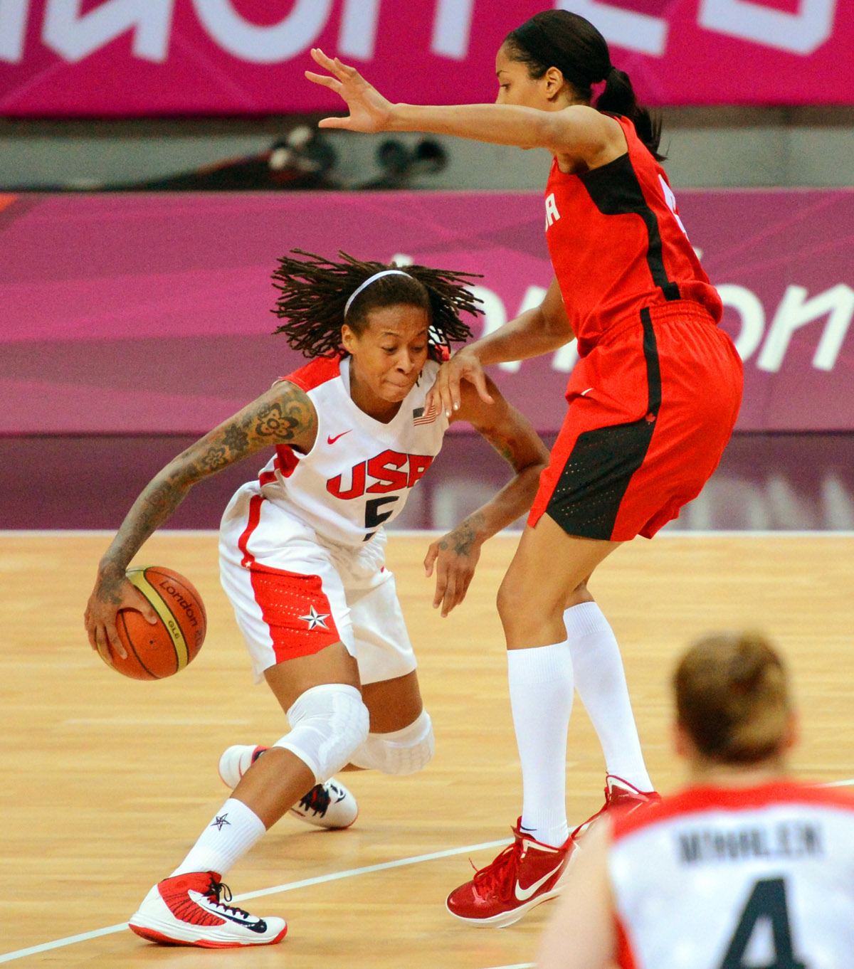 USA Seimone Augustus dribbles past Canada defender in the first quarter of the quarter final game of the women's basketball competition. The USA went on to win 91-48.(AP Photo/Dick Druckman)