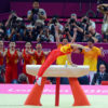 China gymnist, C Zhang, finishes a gold medal performance on the pommel horse as his teammates cheer him on. China went on to win the Gold Medal in the team competition in the North Greenwich Arena in the London Olympics.(AP Photo/Dick Druckman)