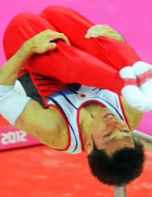 Japan gymnist, Kazuhito Tanaka dismouints from the parallel bars in the men's team competition at the North Greenwich Arena. Japan went on to win the Silver Medal.(AP Photo/Dick Druckman)