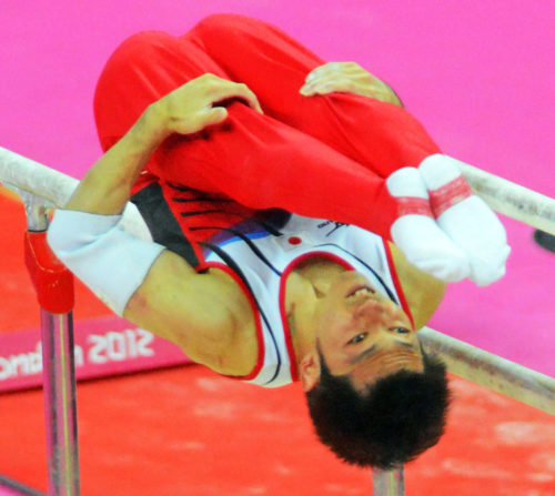 Japan gymnist, Kazuhito Tanaka dismouints from the parallel bars in the men's team competition at the North Greenwich Arena. Japan went on to win the Silver Medal.(AP Photo/Dick Druckman)